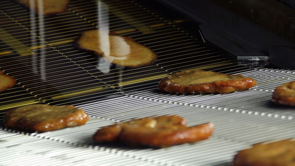 schnitzel on belt in AGF Pro Fryer by alco food machines